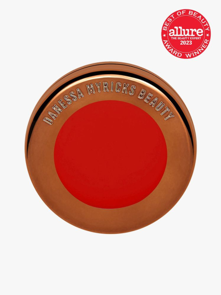 Danessa Myricks Yummy Blurring Balm Flushed in Red Velvet with a red 2023 Allure Best of Beauty Award seal on a gray background